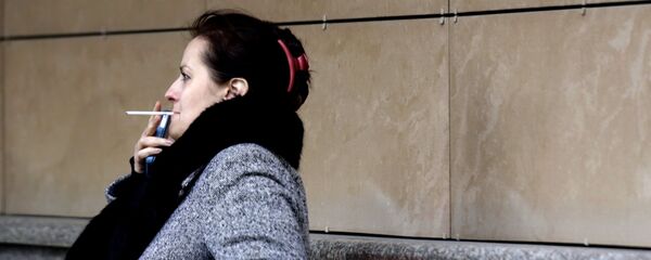 Женщина курит на одной из улиц Москвы. - Sputnik Грузия