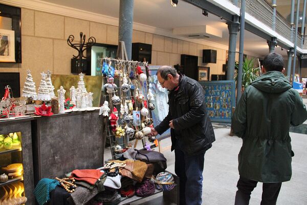 Посетители знакомятся с работами, выставленными на Рождественской ярмарке. - Sputnik Грузия