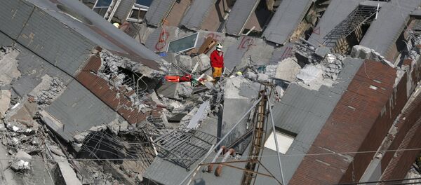Спасатель на развалинах 17-этажного дома, разрушенного землетрясением в Тайнане на юге Тайваня. - Sputnik Грузия