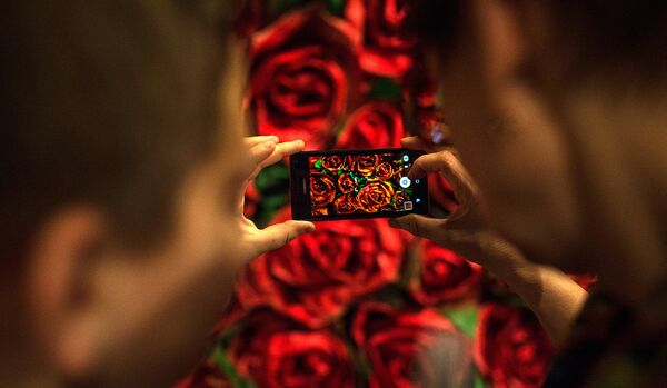Посетители фотографируют стену с изображением роз на открытии мультимедийного проекта Резо Габриадзе Необыкновенная выставка. - Sputnik Грузия