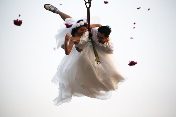 Молодожены, пристегнутые к тросу, летают на свадебной церемонии в День Св. Валентина на курорте в Ратчабури, Таиланд. - Sputnik Грузия