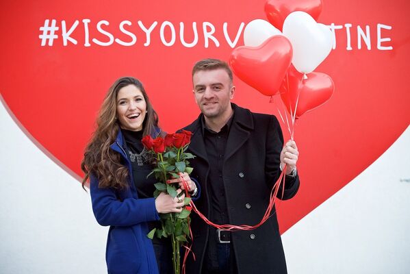 Молодые люди фотографируются у баннера с надписью #kissyourvalentine в День всех влюбленных в Тбилиси. - Sputnik Грузия