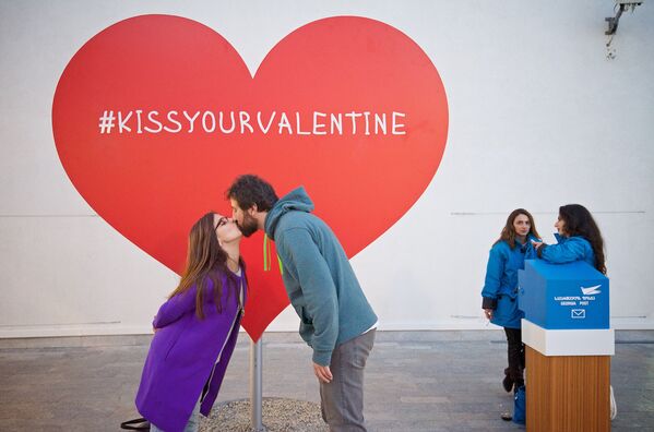 Молодая пара целуется у большого сердца, установленного в одном из тбилисских торговых центров к Дню всех влюбленных. - Sputnik Грузия