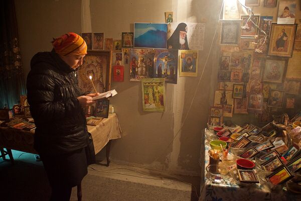 Верующая молится у мироточащих икон в квартире семьи Какошвили. - Sputnik Грузия