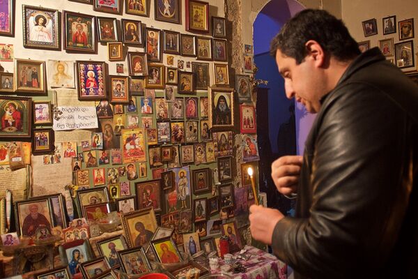 Мужчина молится у мироточащих икон в квартире семьи Какошвили. - Sputnik Грузия