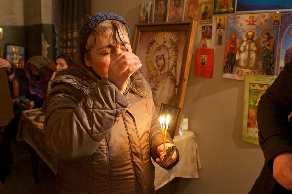 Женщина наносит себе на лоб миро в квартире семьи Какошвили в городе Рустави, где мироточат иконы с изображениями святых. - Sputnik Грузия