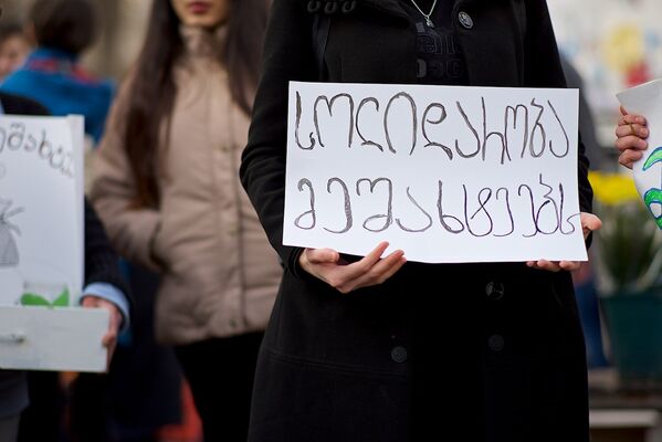 Одна из участниц акции держит в руках плакат с надписью Солидарность шахтерам!. - Sputnik Грузия
