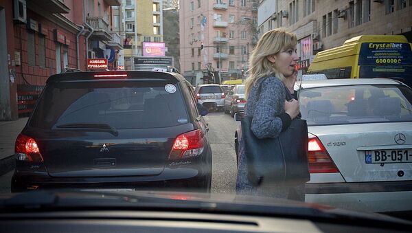 Женщина перебегает дорогу между машинами в Тбилиси - Sputnik Грузия