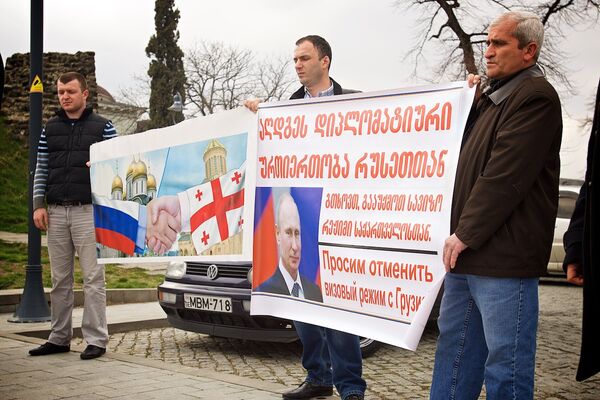 Участники акции держат плакаты с просьбой к властям РФ отменить визовый режим с Грузией и с символическим изображением дружеского рукопожатия между двумя странами. - Sputnik Грузия