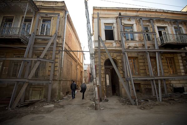 Местные жители проходят между двумя старыми домами на площади Гудиашвили. - Sputnik Грузия