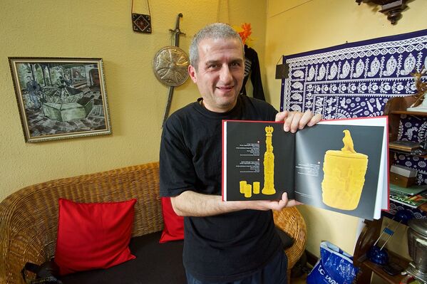 Малхаз Эремашвили демонстрирует альбом с примерами своих работ из воска. - Sputnik Грузия