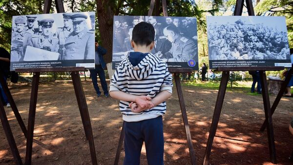 Мальчик разглядывает снимки на фотовыставке, приуроченной к празднованию Дня Победы над фашизмом - Sputnik Грузия