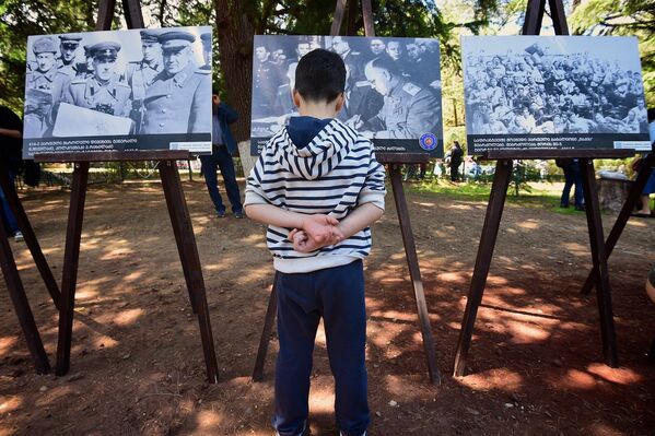 Мальчик разглядывает снимки на фотовыставке в парке Ваке, приуроченной к празднованию Дня Победы над фашизмом. - Sputnik Грузия