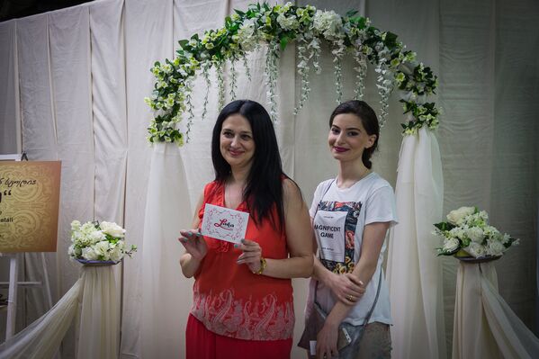 Девушка слева фотографируется на память после получения ваучера на бесплатную организацию свадьбы на Фестивале свадебных платье и аксессуаров в Тбилиси. - Sputnik Грузия
