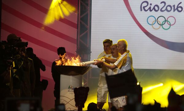 Бывшие бразильские футболисты Адемир да Гия, Ривеллино и Зетти зажигают олимпийский огонь в парке Анемби в Сан-Паулу, Бразилия. - Sputnik Грузия