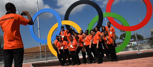 Волонтеры фотографируются у олимпийских колец в Олимпийском парке в Рио-де-Жанейро - Sputnik Грузия