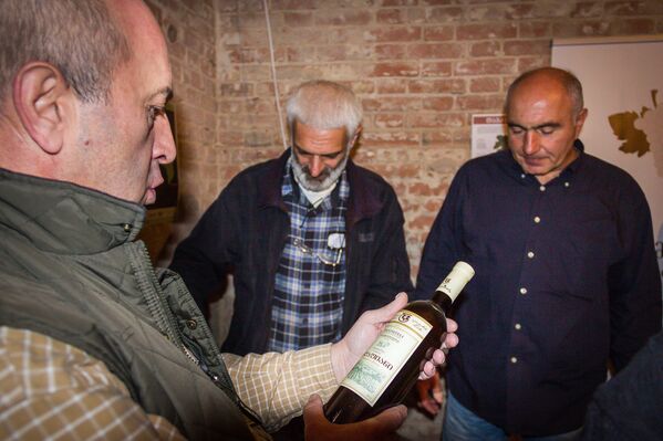 Посетители изучают вина, представленные на презентации продукции малых и средних винных погребов Грузии. - Sputnik Грузия