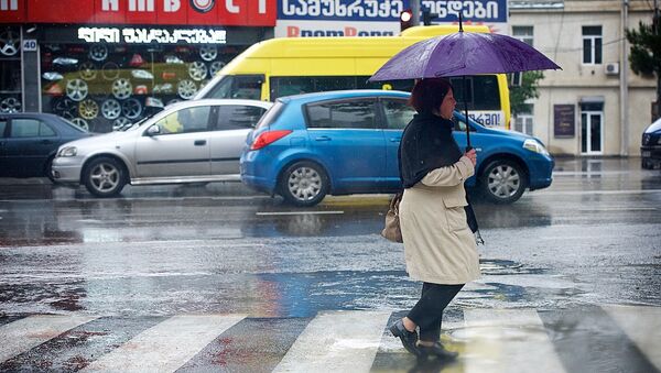 Женщина с зонтом переходит дорогу в дождь - Sputnik Грузия