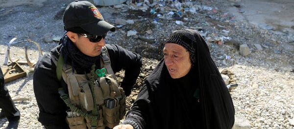 Сотрудник Сил безопасности Ирака беседует с жительницей Мосула на месте разрушений от взрывов после атак ИГ - Sputnik Грузия
