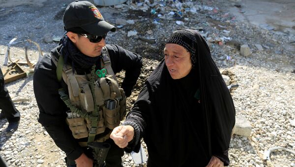 Сотрудник Сил безопасности Ирака беседует с жительницей Мосула на месте разрушений от взрывов после атак ИГ - Sputnik Грузия
