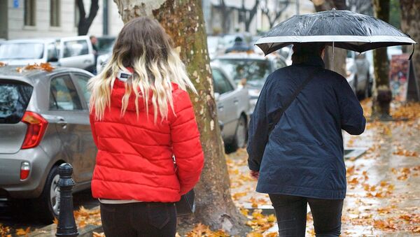 Женщины идут под дождем по одной из улиц в центре грузинской столицы - Sputnik Грузия