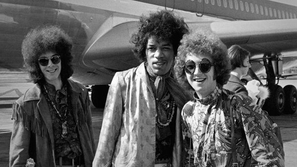Джими Хендрикс (в центре), бас-гитарист Ноэл Реддинг (слева) и ударник Мич Митчелл (справа) на фото, сделанном в 1967 году в аэропорту Хитроу - Sputnik Грузия