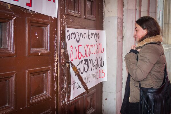 Движение 115 расклеило свои плакаты прямо на дверях аудиторий вуза. Одна из учащихся читает призывы активистов студенческого движения. - Sputnik Грузия
