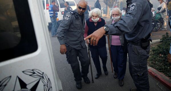 Сотрудники израильской полиции помогают жителям Хайфы в эвакуации из опасных районов на севере города - Sputnik Грузия