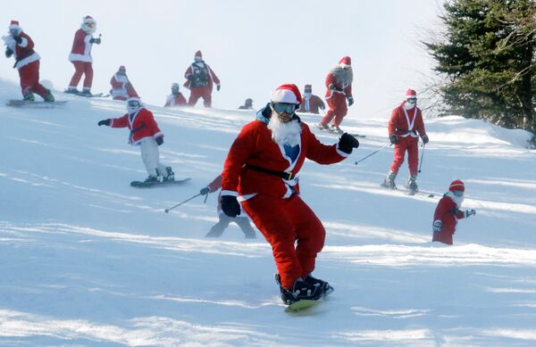 Лыжники и сноубордисты спускаются с горы в ходе благотворительного рождественского заезда Санта Клаусов в штате Мэн, США - Sputnik Грузия