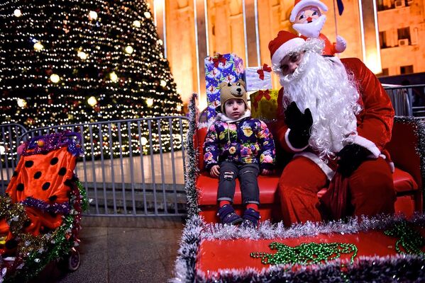 Ребенок фотографируется на память с Дед Морозом у главной новогодней елки Грузии на проспекте Руставели - Sputnik Грузия