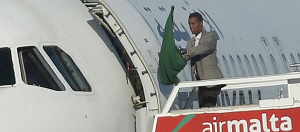 Один из угонщиков самолета Afriqiyah Airways машет ливийским флагом эпохи Кадаффи в аэропрту Мальты - Sputnik Грузия