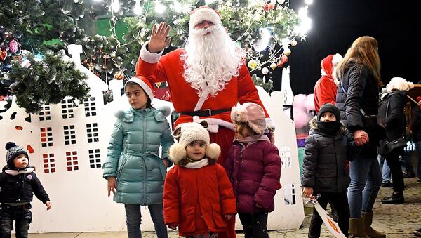 Санта Клаус фотографируется с детьми у новогодней елки в одном из парков грузинской столицы - Sputnik Грузия
