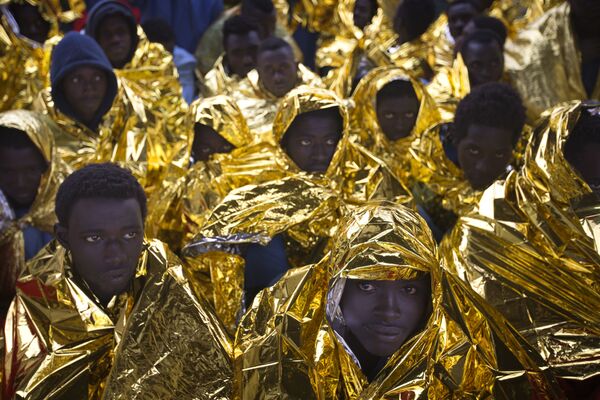 Мигранты из Африки кутаются в пледы, которые им выдали на борту итальянского судна Golfo Azzurro после спасательной операции. На этой неделе спасатели из итальянского НКО Proactiva Open Arms вытащили из воды 299 человек, которые пытались добраться к европейским берегам на резиновых лодках - Sputnik Грузия