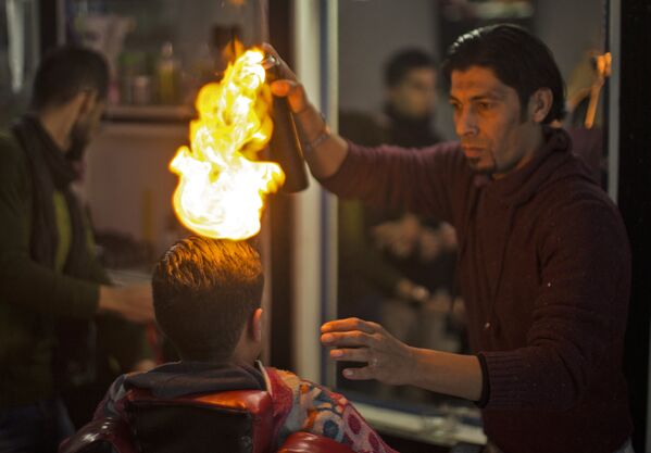 Палестинский мастер Рамадан Эдва поджигает волосы, когда укладывает готовую прическу - Sputnik Грузия