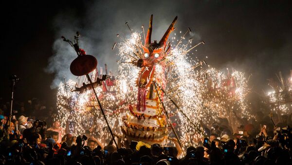 Люди смотрят на огненного дракона, сделанного из петард, китайских фонариков и фейерверков во время исполнения праздничного танца дракона участниками Фестиваля фонарей в провинции Гуандун в Китае. - Sputnik Грузия