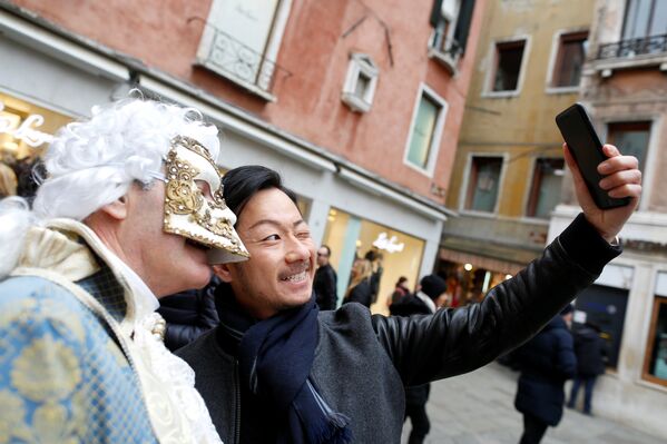 Турист снимает селфи на память с участником Венецианского карнавала в маскарадном костюме - Sputnik Грузия