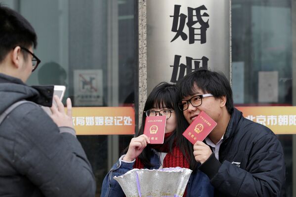 Молодожены показывают свидетельства об официальной регистрации брака, зарегистрированного в День Святого Валентина в Пекине, Китай - Sputnik Грузия
