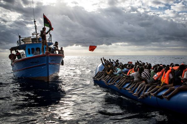 Ливийские рыбаки бросают спасательные жилеты мигрантам, которых контрабандисты, организовавшие переправу, направили в открытое море на резиновой лодке к берегам Италии. Это фото Мэтью Уилкока из MOAS.eu, сделанное в серии “Средиземноморская миграция”, завоевало третью премию World Press Photo Awards 2017 в категории “Экстренные новости” - Sputnik Грузия