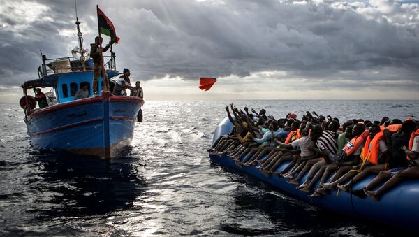 Ливийские рыбаки бросают спасательные жилеты мигрантам, которых контрабандисты, организовавшие переправу, направили в открытое море на резиновой лодке к берегам Италии. Это фото Мэтью Уилкока из MOAS.eu, сделанное в серии “Средиземноморская миграция”, завоевало третью премию World Press Photo Awards 2017 в категории “Экстренные новости” - Sputnik Грузия
