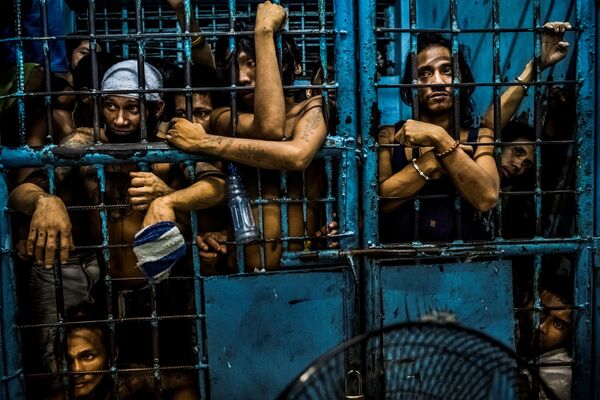 Задержанные в полицейском участке в Маниле, Филиппины, смотрят, как полицейские “обрабатывают” подозреваемых в торговле наркотиками. Это фото Даниэла Бэрехулака из New York Times завоевало первую премию World Press Photo Awards 2017 в категории “Общие новости” - Sputnik Грузия