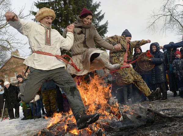 Люди прыгают через костер во время празднования Масленицы во Всеволожске недалеко от Санкт-Петербурга. Масленица предшествует началу Великого поста - Sputnik Грузия