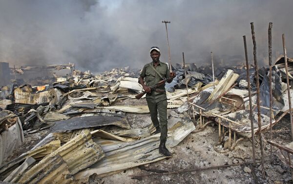 Сомалийский солдат идет через обломки на главном рынке столицы Сомали - Могадишо, после того, как его охватил пожар. Возгорание началось на золотом базаре и затем огонь охватил весь рынок - Sputnik Грузия
