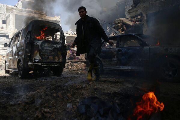 Представитель отряда гражданской обороны бежит по городу Дума (недалеко от Дамаска, Сирия) среди горящих машин - Sputnik Грузия