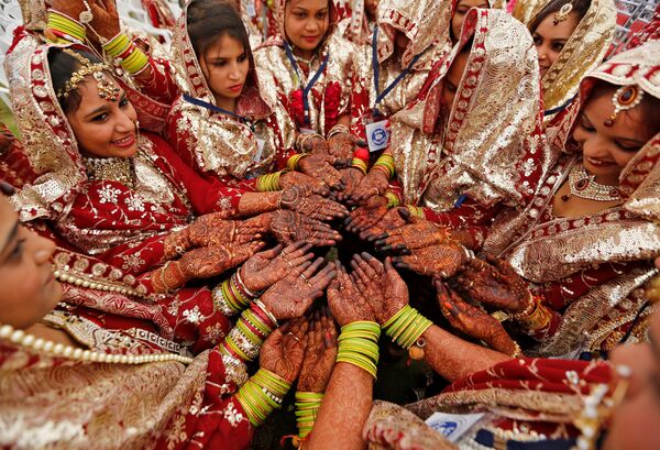 სარძლოები უჩვენებენ ხნით შეღებილ ხელებს, სანამ საქორწინო ფიცს დადებენ საყოველთაო დაოჯახების ცერემონიაზე აჰმადაბადში, ინდოეთი. ამ დღეს ერთდროულად 131-მა მუსლიმმა წყვილმა შექმნა ოჯახი - Sputnik საქართველო