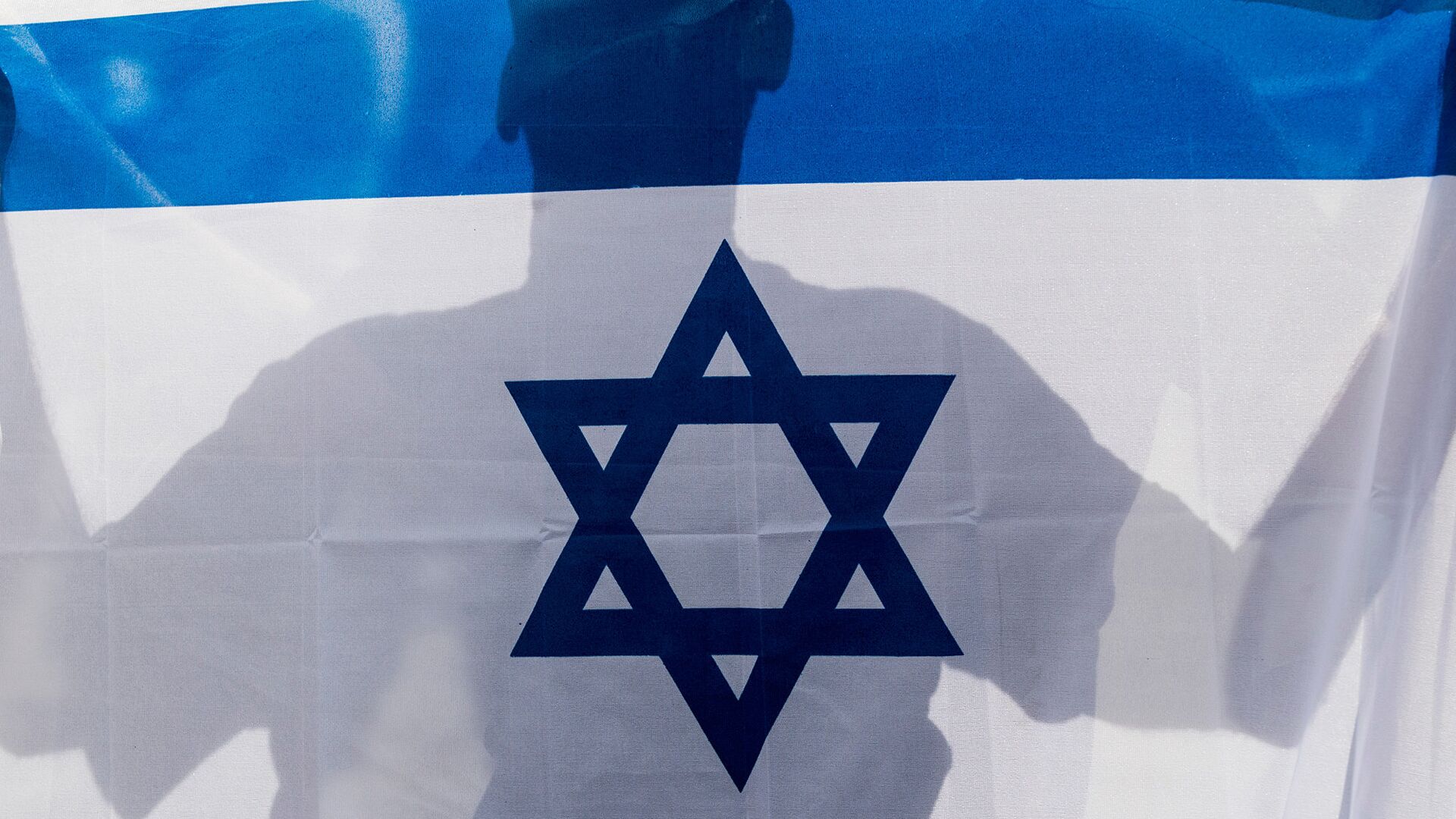Человек держит в руках флаг Израиля - Sputnik Грузия, 1920, 16.03.2022