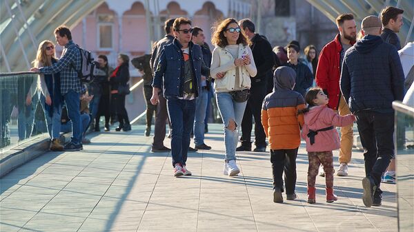 Жители и гости грузинской столицы гуляют весенним днем по мосту Мира в центре Тбилиси - Sputnik Грузия