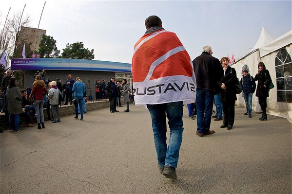 Один из сторонников ЕНД, участвующий в акции у здания телекомпании, идет, обернувшись в флаг с символикой Рустави 2 - Sputnik Грузия