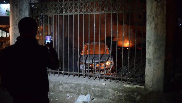 Человек фотографирует на смартфон сожженные в ходе беспорядков в Батуми машины - Sputnik Грузия