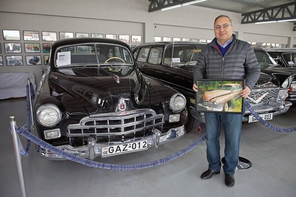 Основатель Тбилисского автомузея, коллекционер Георгий Мамулашвили у автомобиля ГАЗ-12, представленного в частном автомобильном музее в столице Грузии. На снимке - коллекционер наглядно показывает, каким был этот автомобиль до восстановления - Sputnik Грузия