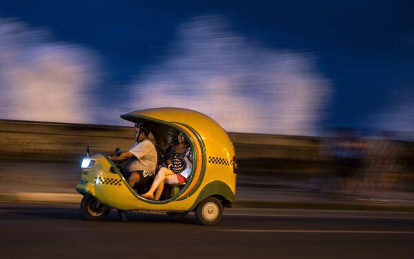 Необычное такси работает на улицах Гаваны, столицы Кубы. Здесь и сегодня можно увидеть велосипедное Коко-такси. Оно рассчитано на двух пассажиров и водителя и, по сути, является велосипедом с пассажирским салоном. Данный вид такси самый медленный и самый пыльный, однако он лучше всего подходит для туристов, желающих ознакомиться с местными достопримечательностями - Sputnik Грузия